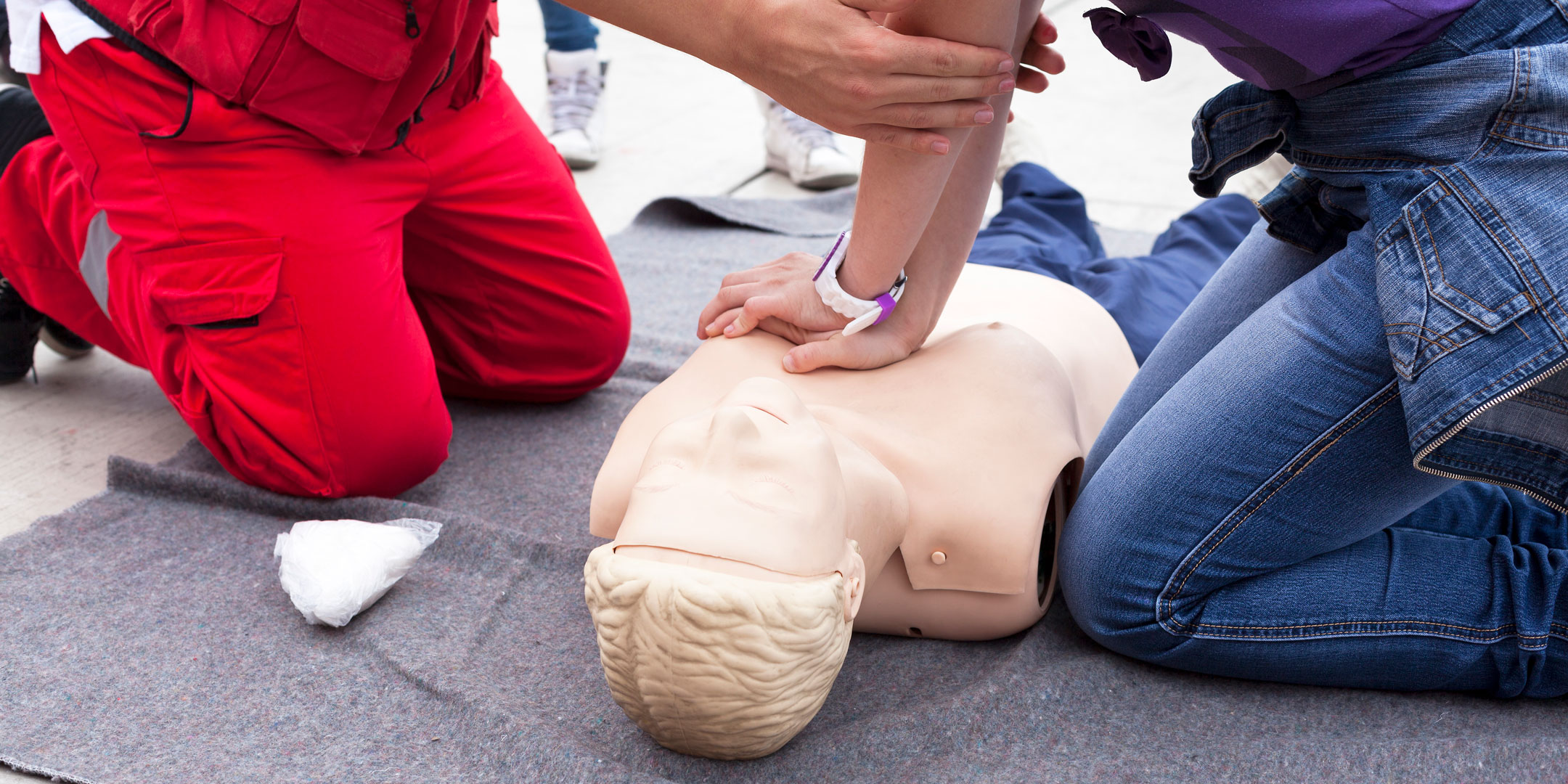 Close-up of CPR instructor helping a student perform CPR on a manikin