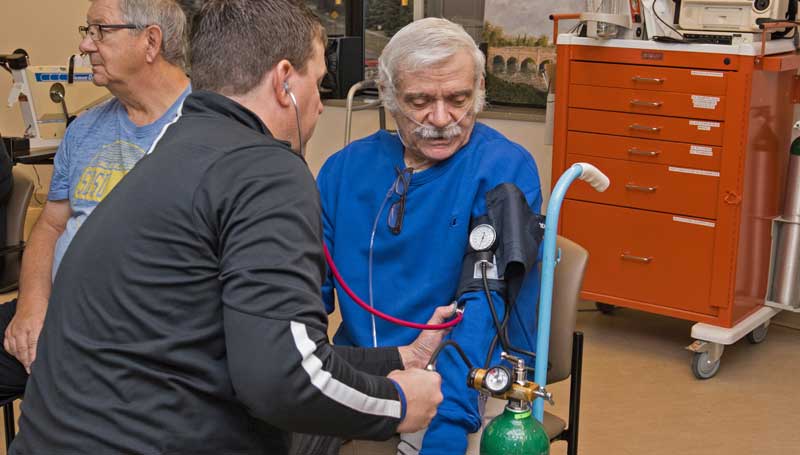 Cardiopulmonary rehab patient have his blood pressure taken by a care provider in the cardiopulmonary rehab gym