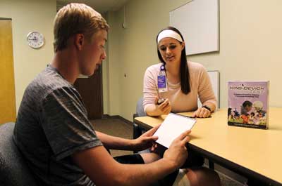 A teenage athlete reads cards from a concussion screening test administered by an occupational therapist