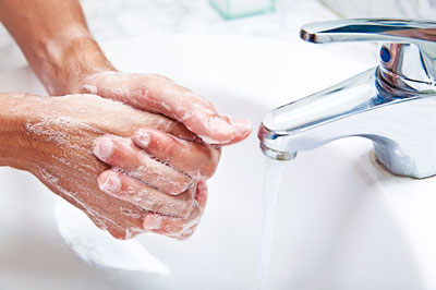 hands lathered with soap being washed in a sink with a running faucet