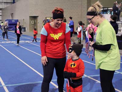 Mother and son dressed like super heroes receive medals from the 2018 Super Hero 5K.