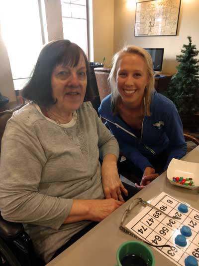 Resident Carol Olson poses with her adoptive SDSU student, Sydney Wilson, during a round of bingo hosted by the SDSU Adopt-a-Grandparent club at The Neighborhoods at Brookview nursing home. As club members, SDSU students commit to volunteer for one year and spend a minimum of one-hour per month with their matched resident. The program helps give residents a sense of purpose and belonging while allowing them to build a personal bond and relationship with a young person.