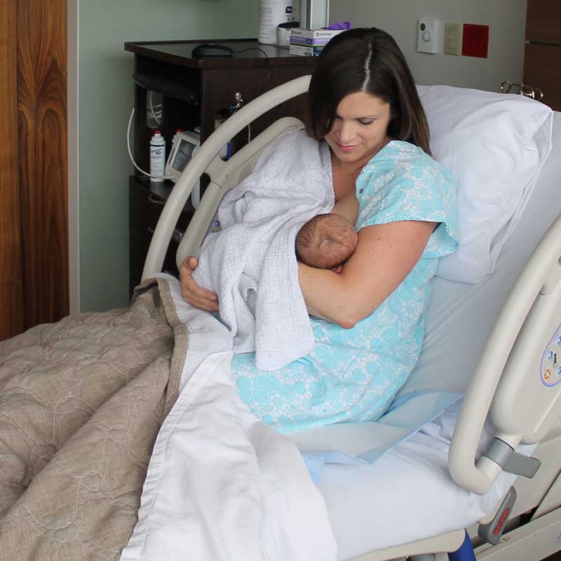 New mom breastfeeding baby in an obstetrics hospital room