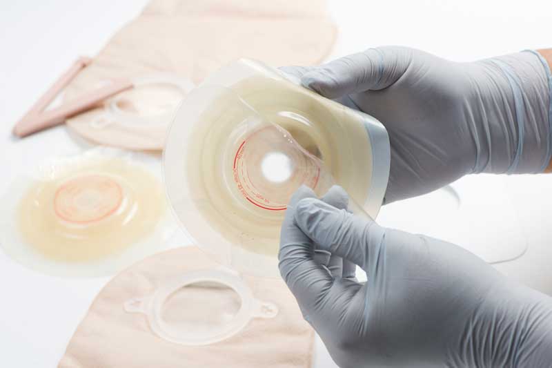 A close up of hands examining ostomy supplies
