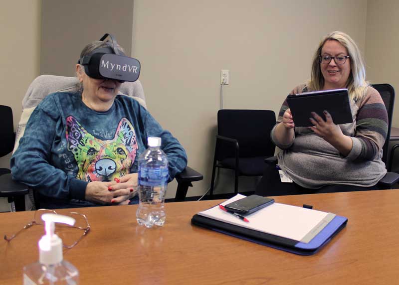 Hospice Volunteer Jan Olson wears a VR headset and watches rabbits playing, the virtual reality experience selected by Social Worker Donna Bumann during a recent VR training. The new VR program will allow hospice patients to have therapeutic experiences in the comfort of their own home. 