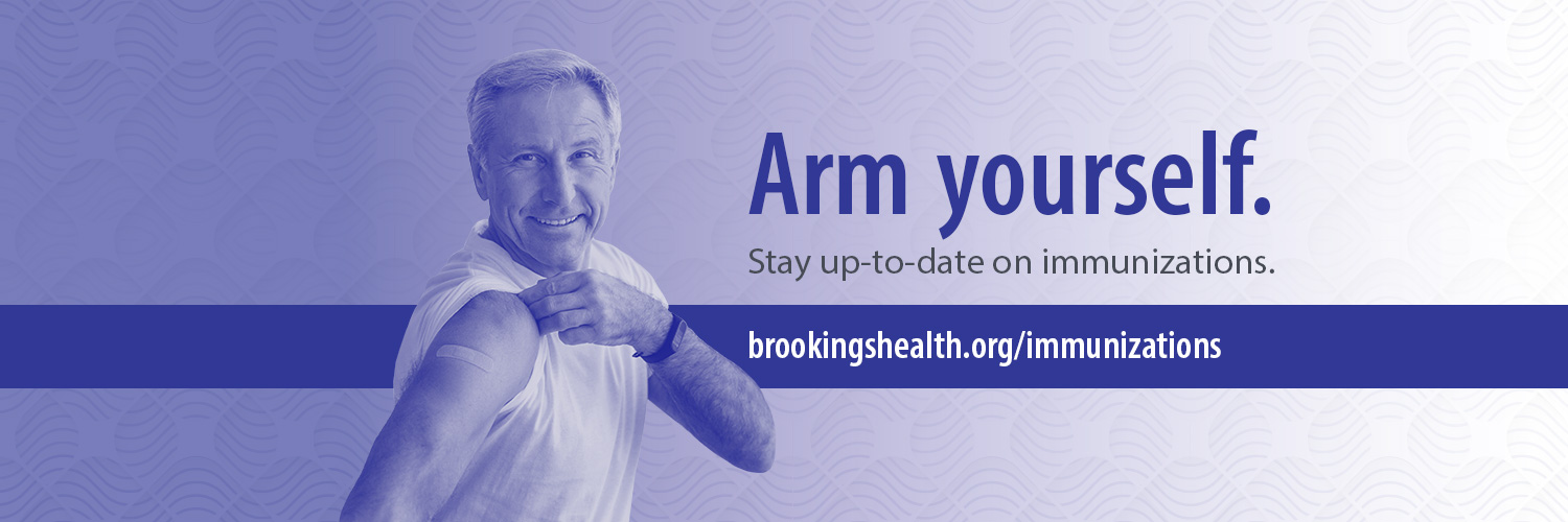 Image of a man in his 60s rolling up his sleeve, showing where he has a band-aid from his flu shot.