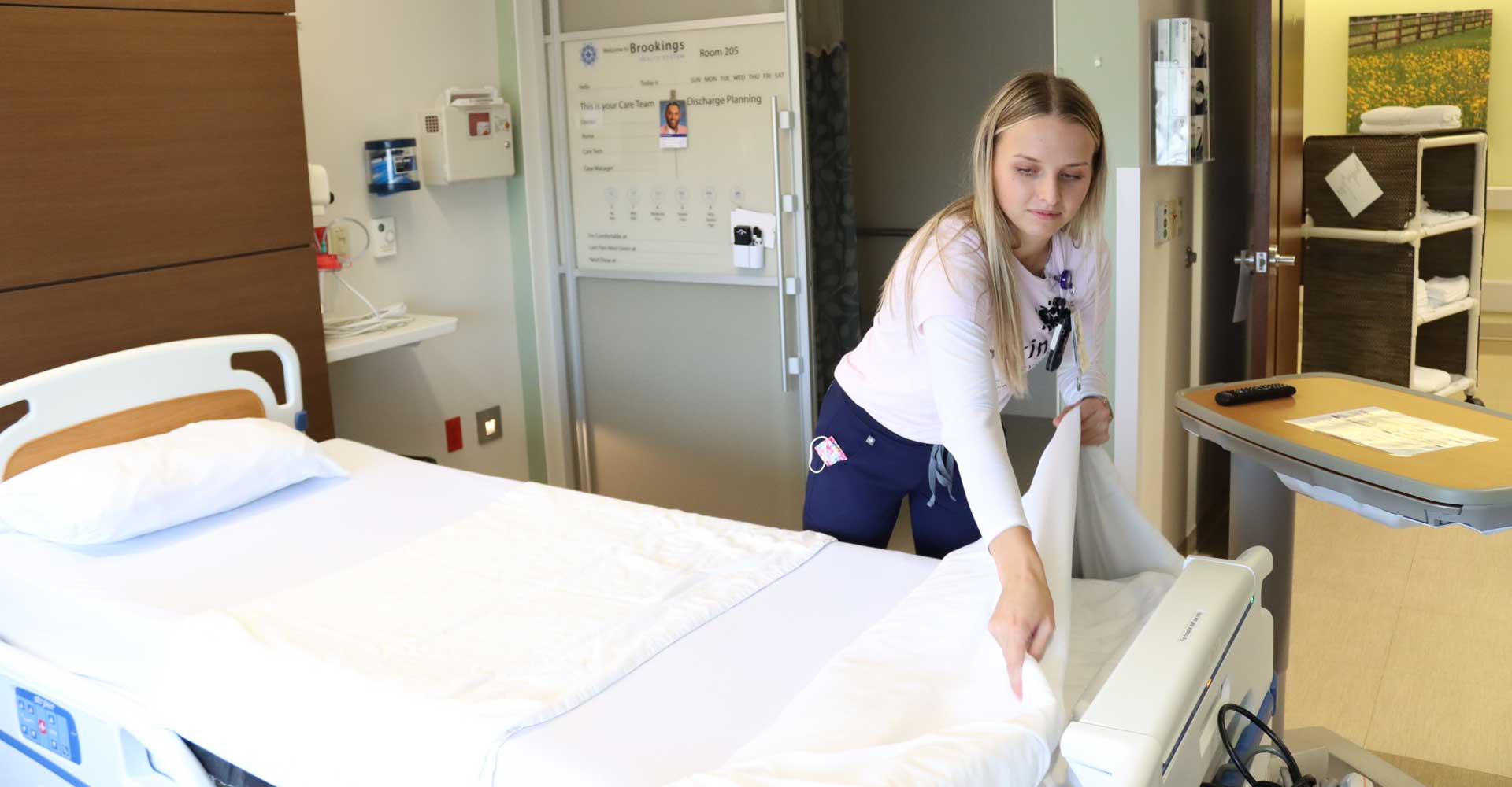 Patient care tech Maddie makes a bed in a room in the inpatient care unit