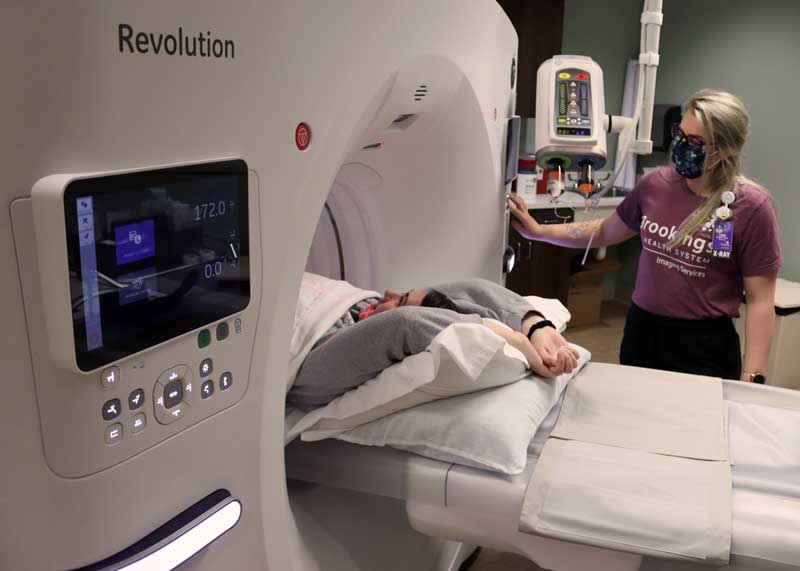 CT technologist assisting patient in computerized tomography tube