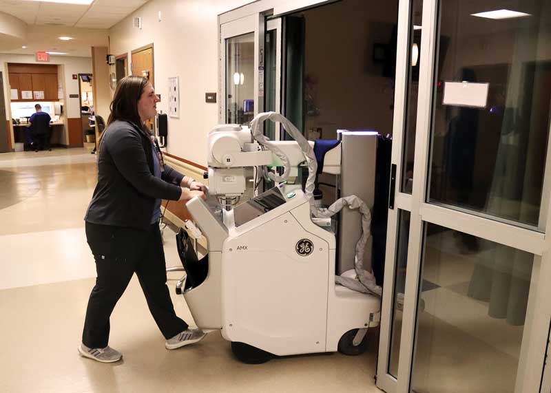 Radiology Technologist Josi Walz transports Brookings Health System’s new GE AMX Navigate portable X-ray into an ER patient room. The new portable X-ray system produces higher quality diagnostic images while using less radiation dose. Portable X-ray machines can scan patients at the bedside rather than moving patients who are injured or having limited mobility to separate exam room. The new system also uses artificial intelligence to check image quality and flag potentially critical conditions.