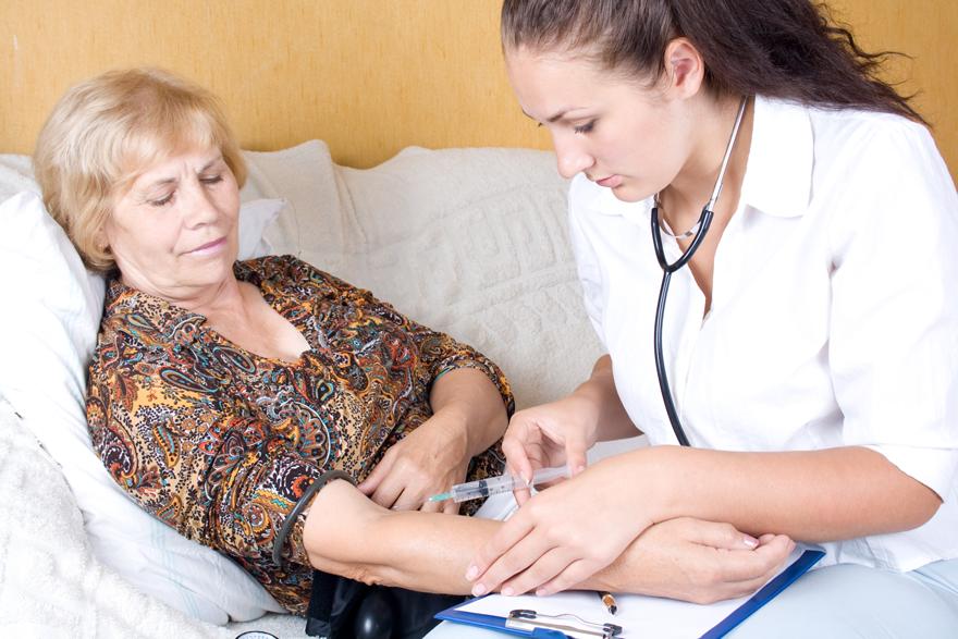 Hospice nurse administering a shot to a patient at home in bed
