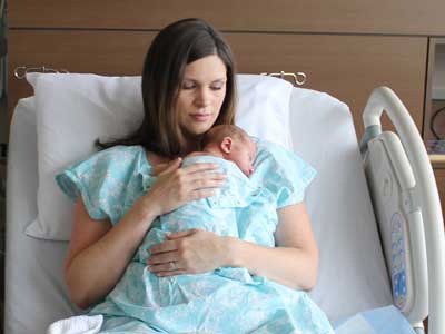 Mother in a hospital bed, snuggling her baby skin-to-skin