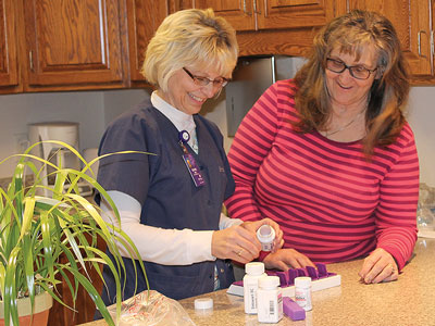 Nurse filling pill box in patient's kitchen
