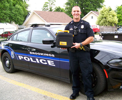 Brookings Police Department Patrol Officer Damian Weets holds one of the current portable AED units purchased in 2001 for department vehicles. Brookings Health System Foundation plans to raise funds at its eighth annual Aiming to Inspire Health sporting clays tournament to replace the old technology with state-of-the-art AEDs to better serve the community.