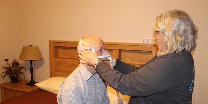 Sleep lab technologist fitting patient with sleep mask