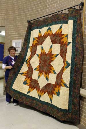 Mona Dykhouse, LPN at Brookview Manor, stands next to the quilt she sewed and donated to help raise money for Brookview Manor's activity fund.