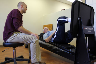 Wendell Nelson of Lake Preston works on the new Shuttle MVP Pro machine under the watchful eye of Physical Therapist Gavin Weber in Brookings Health System’s new physical therapy gym.